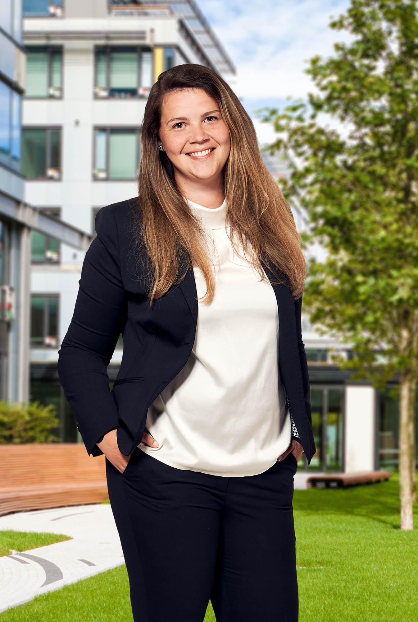 Portrait Bildausschnitt Amerikanisch, lächelnde Frau in dunklem Blazer und heller Bluse, stehend, draußen, Innenhof im Hintergrund